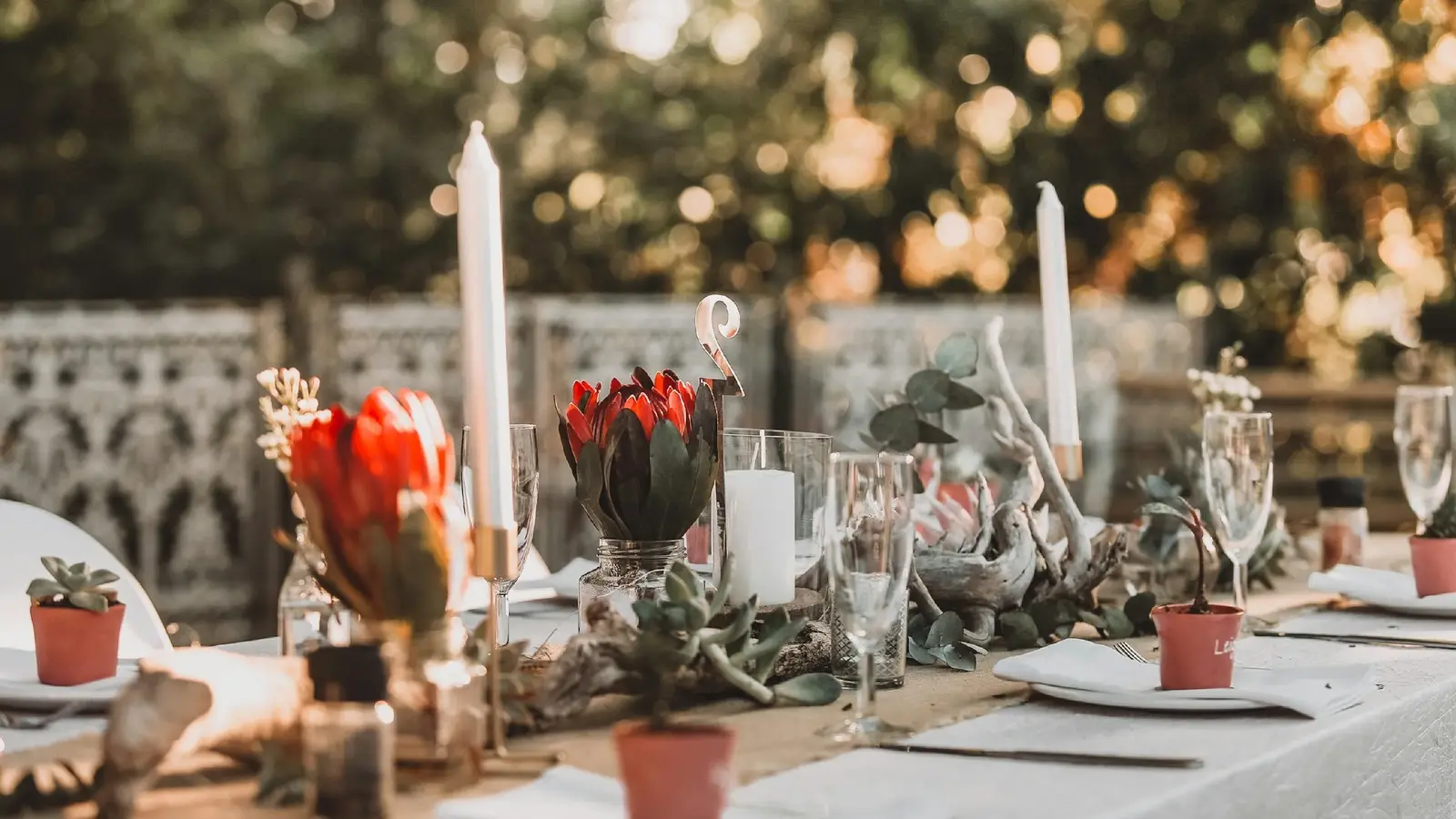 Candlelit wedding reception table set with flowers, glassware, and place settings